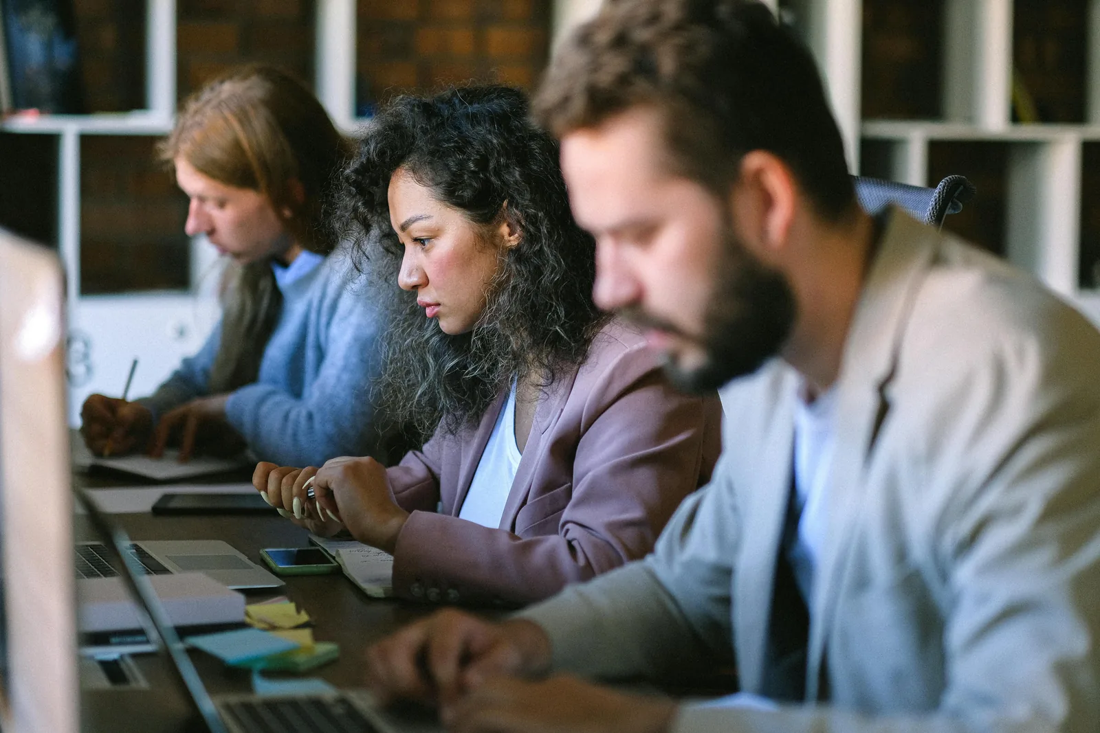 A subject matter expert working at a laptop alongside colleagues.